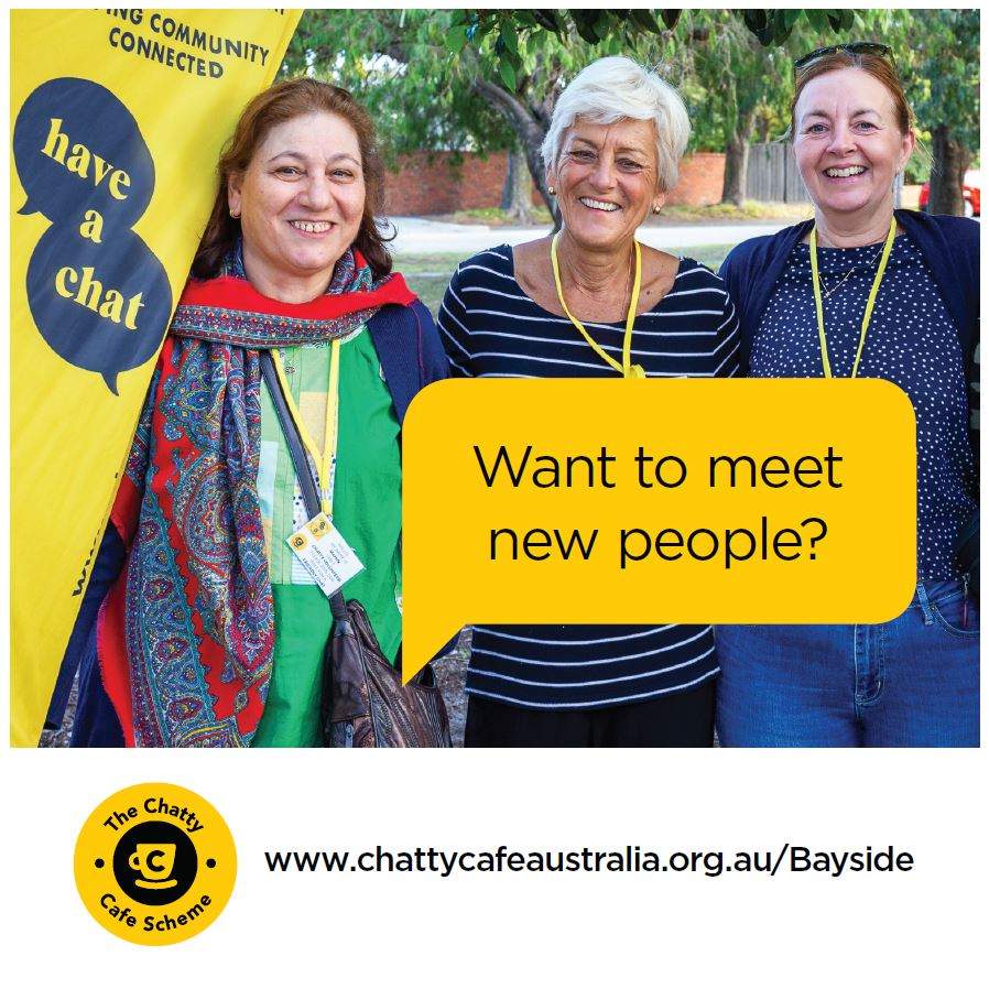 Three women beside a Chatty Cafe banner