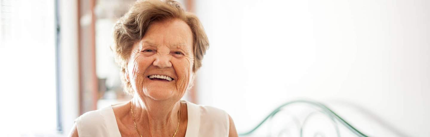 Senior lady wearing white singlet, looking at camera smiling 
