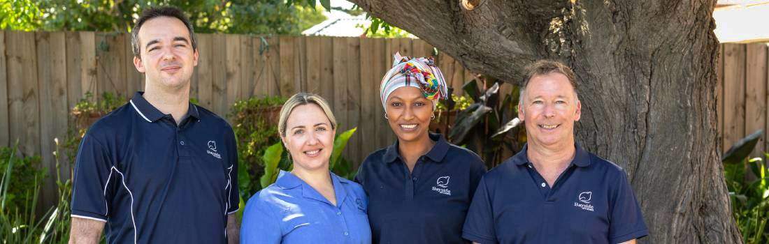 Image of four Bayside Care and Support care workers looking at the camera smiling