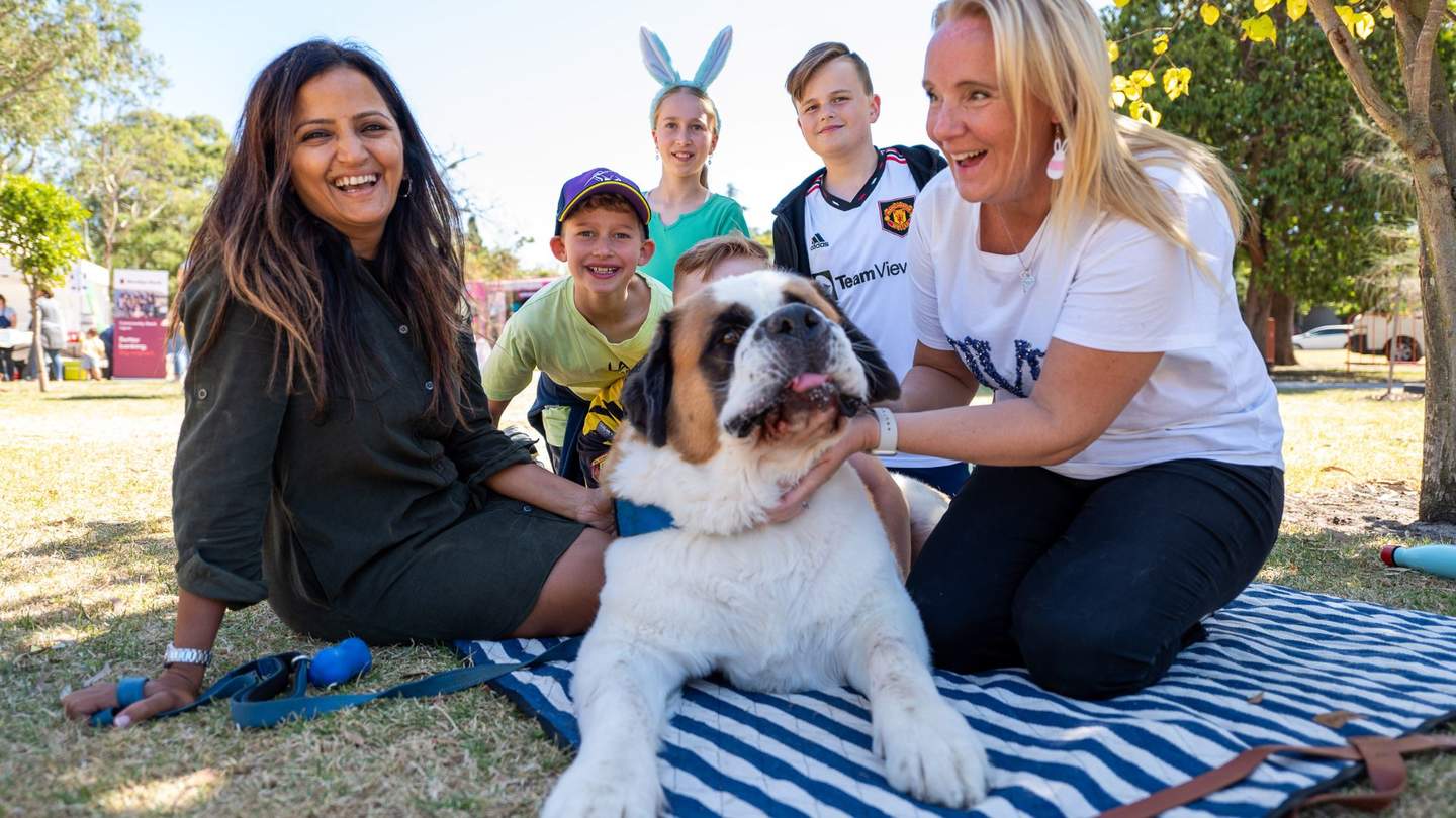 Family and doggo on a picnic rug at Easter event.