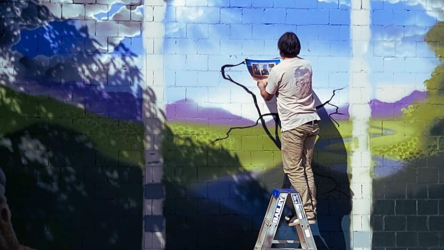 Artist painting mural on wall.