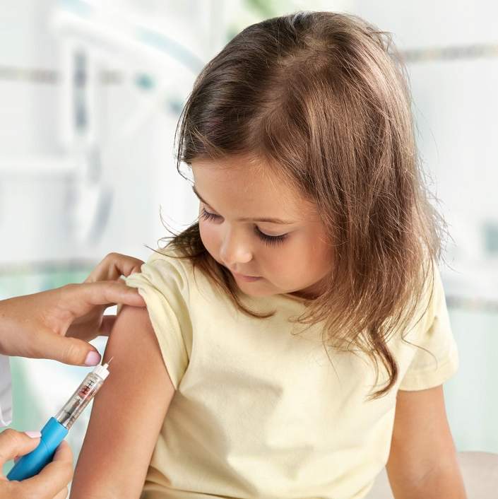 Little girl receiving a flu shot in her arm.