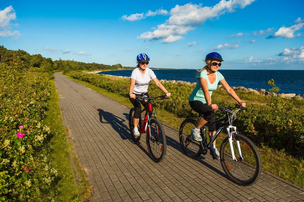 Two female people riding bicycles next to the Bay