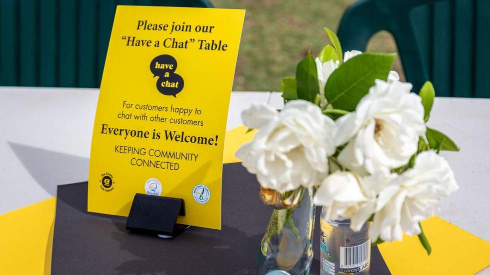 Yellow Chatty Café poster on a table with flowers
