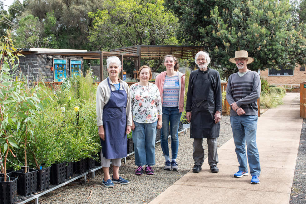 Three women and two men volunteers standing at the Bayside Community Nursery surrounded by greenery