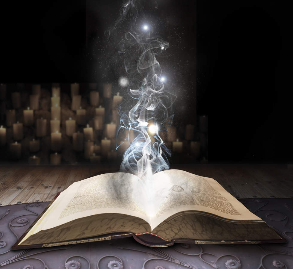Open book with magic smoke coming out of it with candles in background