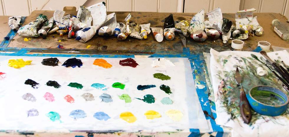 Tubes of paint with swatch colours laid out on an artists table