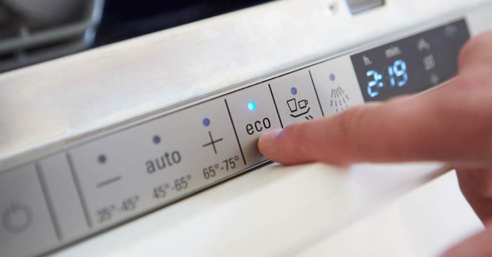 A finger pressing the eco cycle on an energy efficient dishwasher