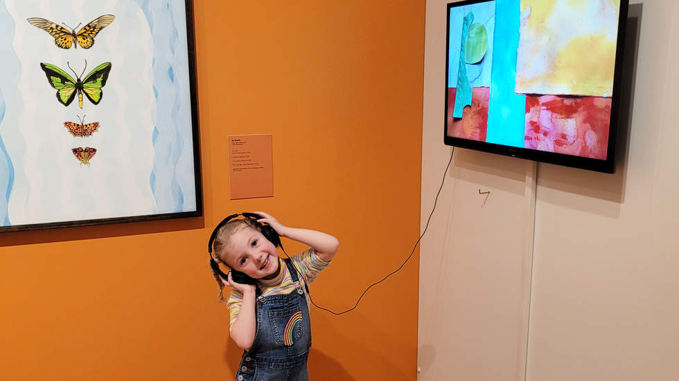 Little girl wearing headphones and watching an animation at Bayside Gallery.