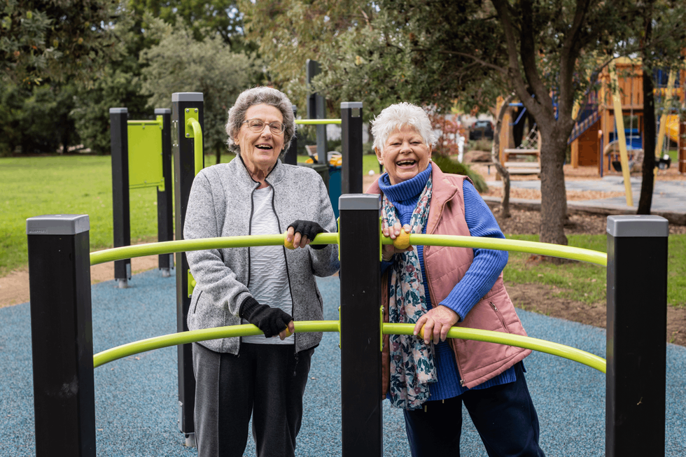 Maureen and Jackie smiling while using healthy ageing exercise equipment at playground