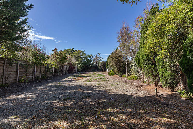 Vacant land with a timber fence on one side and trees on the other side 