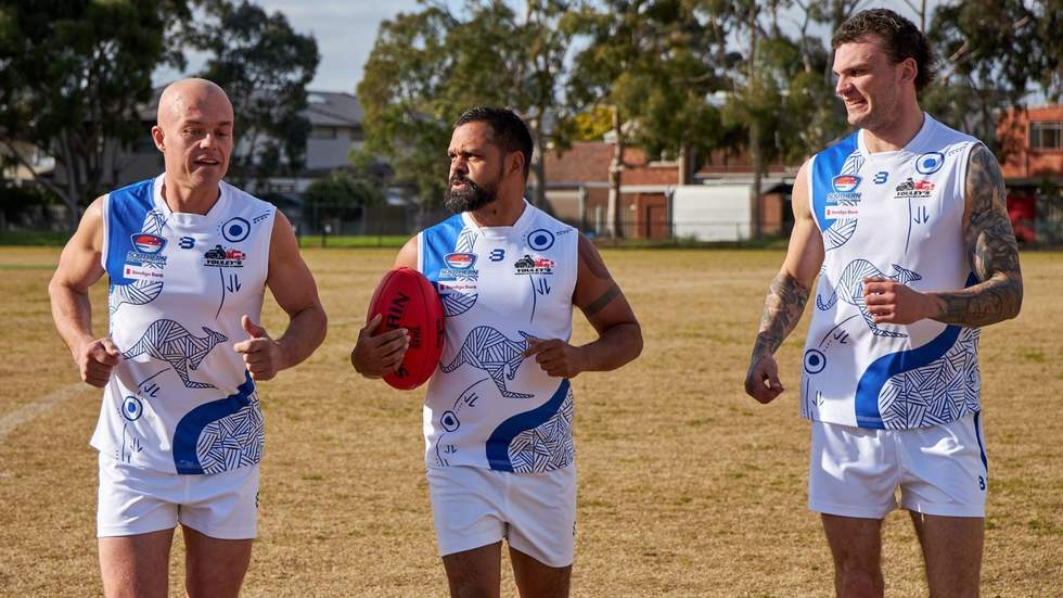 Three AFL players running and chatting in the oval