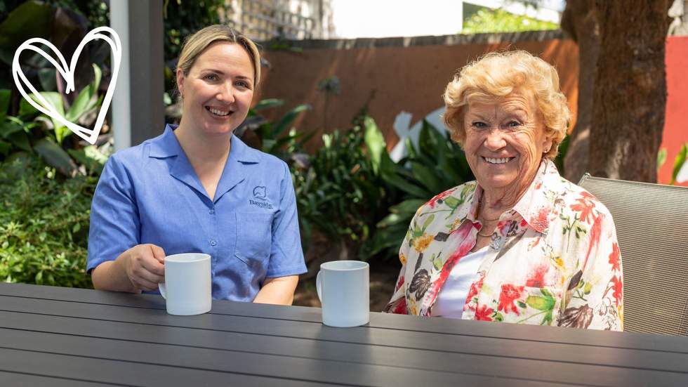 A smiling carer and senior lady having a cuppa.