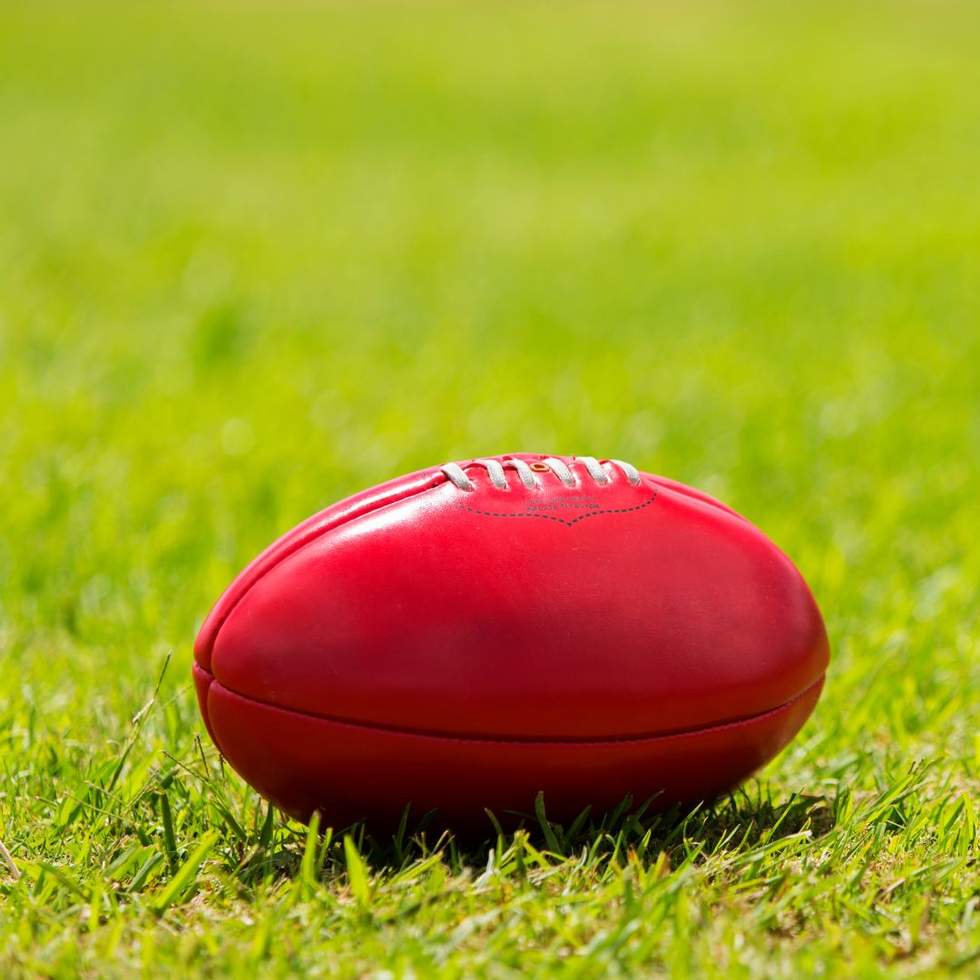 A read Aussie Rules football on the grass