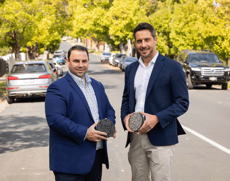 Two men smiling while carrying pieces of renewable asphalt 