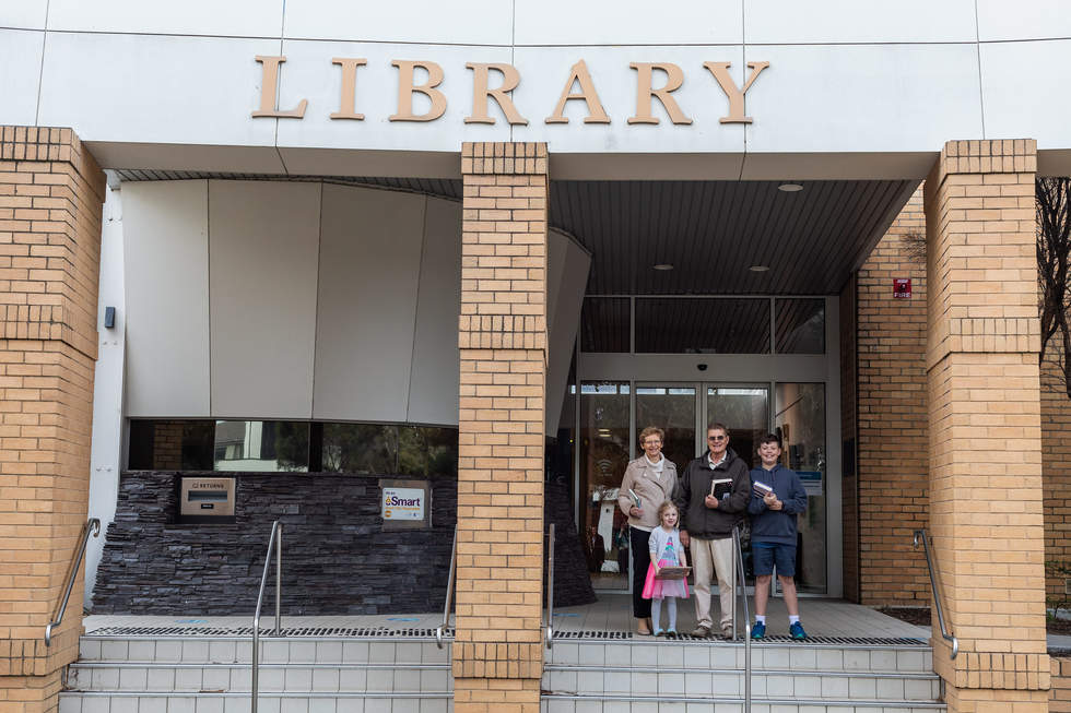 A family of four standing on the steps at the entrance to Beaumaris Library