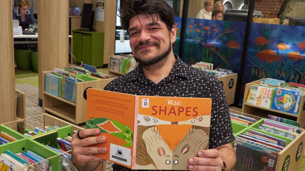 Trent the librarian holding up a book called Shapes.
