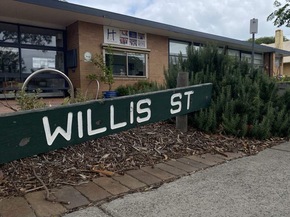 Green Willis Street sign with large white writing in the foreground of Hampton Community Centre