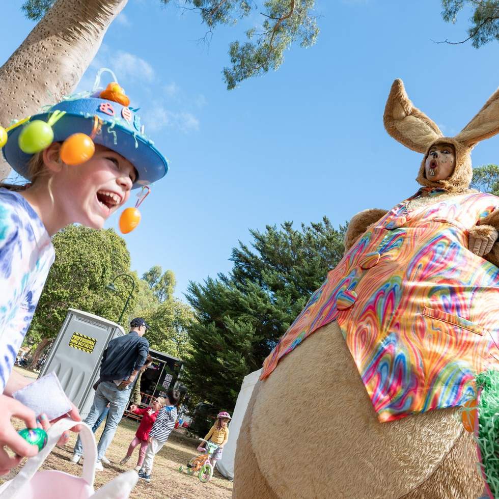 A laughing child with an Easter hat and a giant rabbit kids entertainer