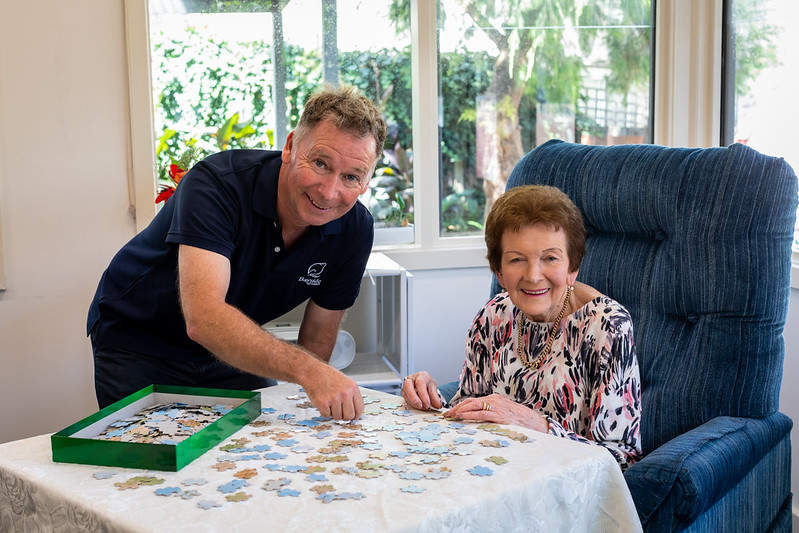 David and Doreen smiling at camera while putting a puzzle together