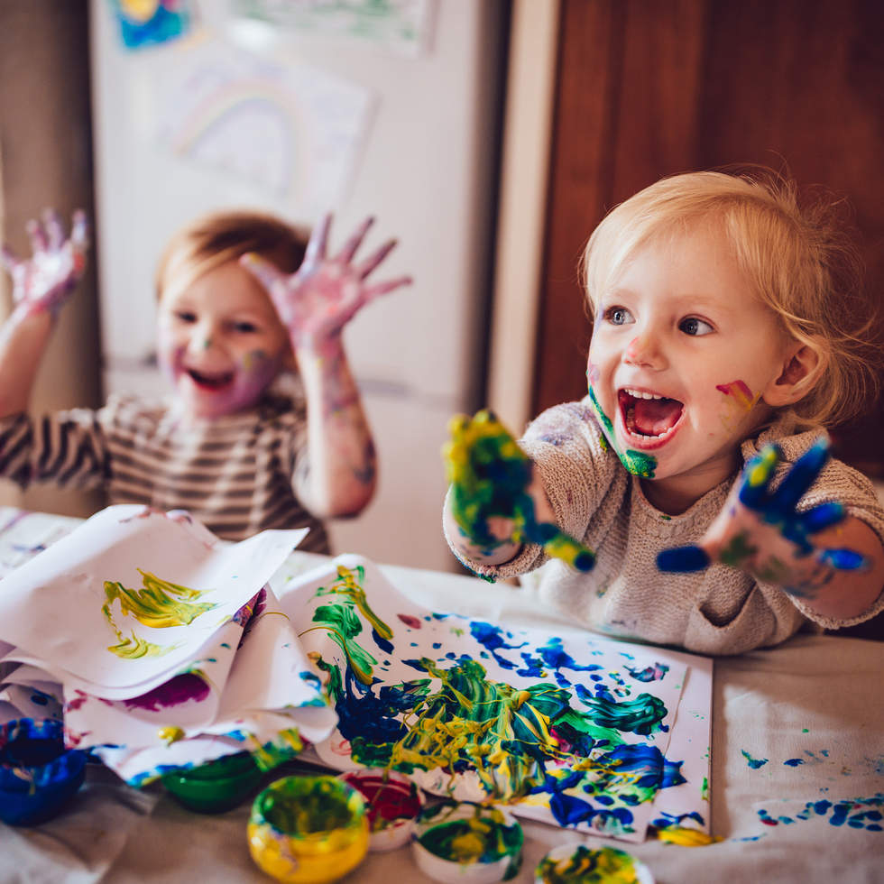 Two children with paint on their hands having fun.