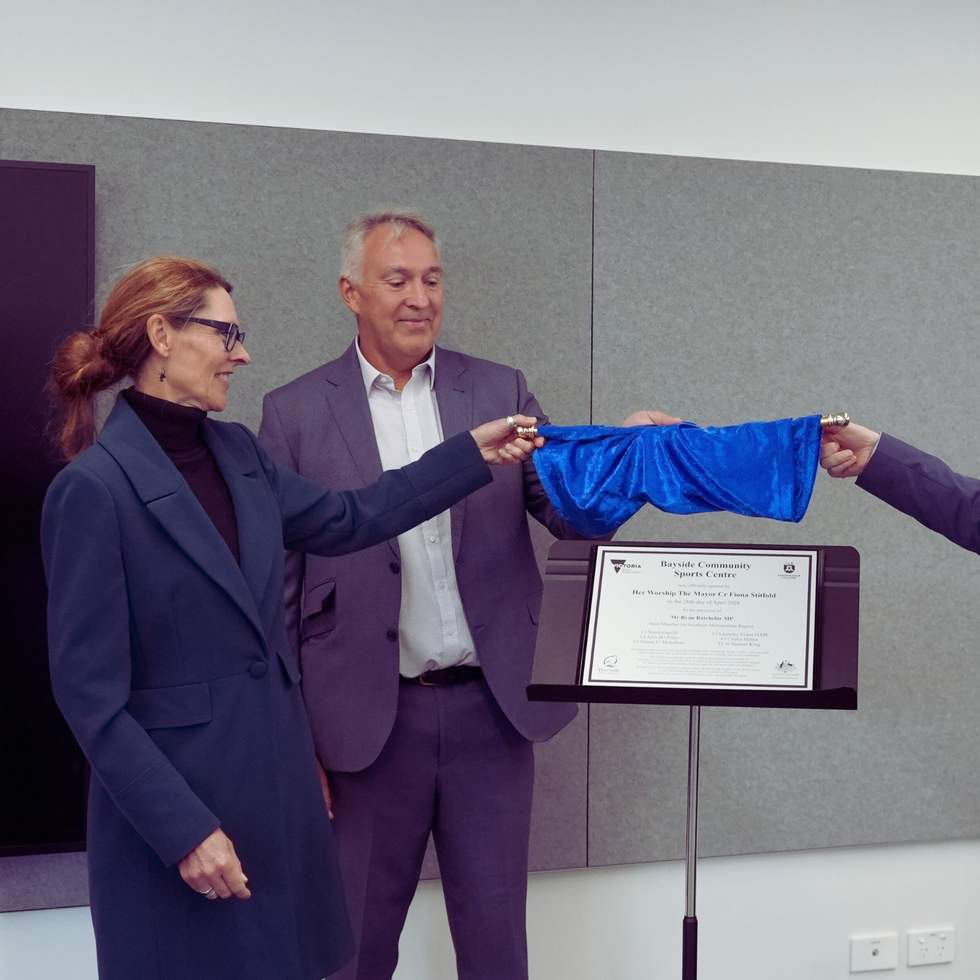 Three people unveiling a plaque.